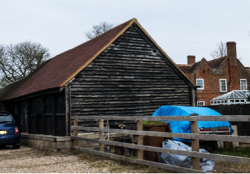Black weatherboarded barn with red clay roof tiles 