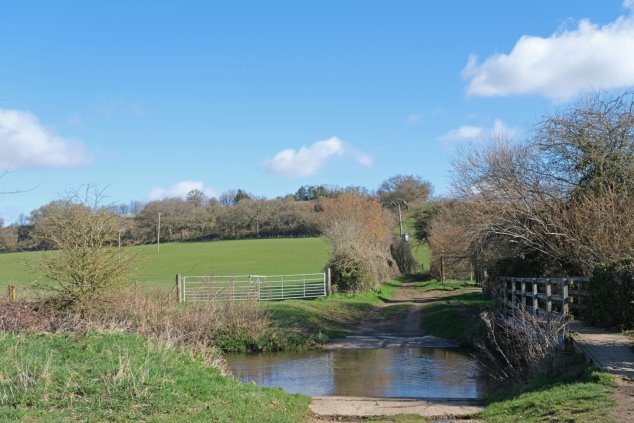  Figure 21: View 2 From Ford looking along UCR2 looking north - river crossing in foreground with ford and raised footpath to right  - green fields and hedges beyond
