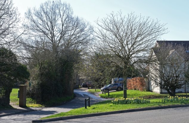 View 10 From St Albans Road looking south east on Cowards Lane - entrance to park , green triangle with daffodils and homes beyond