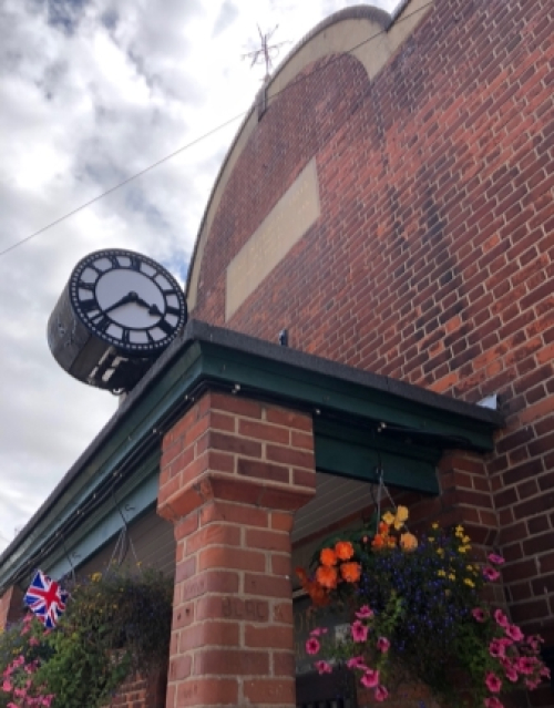 Front of Peace Memorial Hall - red brick with black and white barrel clock above canopied doorway