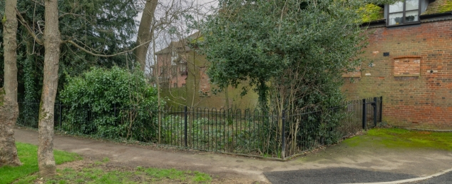 Small green area boarded by round topped black metal railings to delineate the ancient 'pound' enclosure